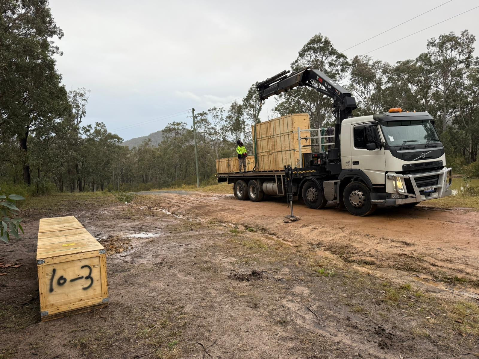 Crane truck delivering numbered Beyond Yurt crates on site, ready for modular yurt assembly.