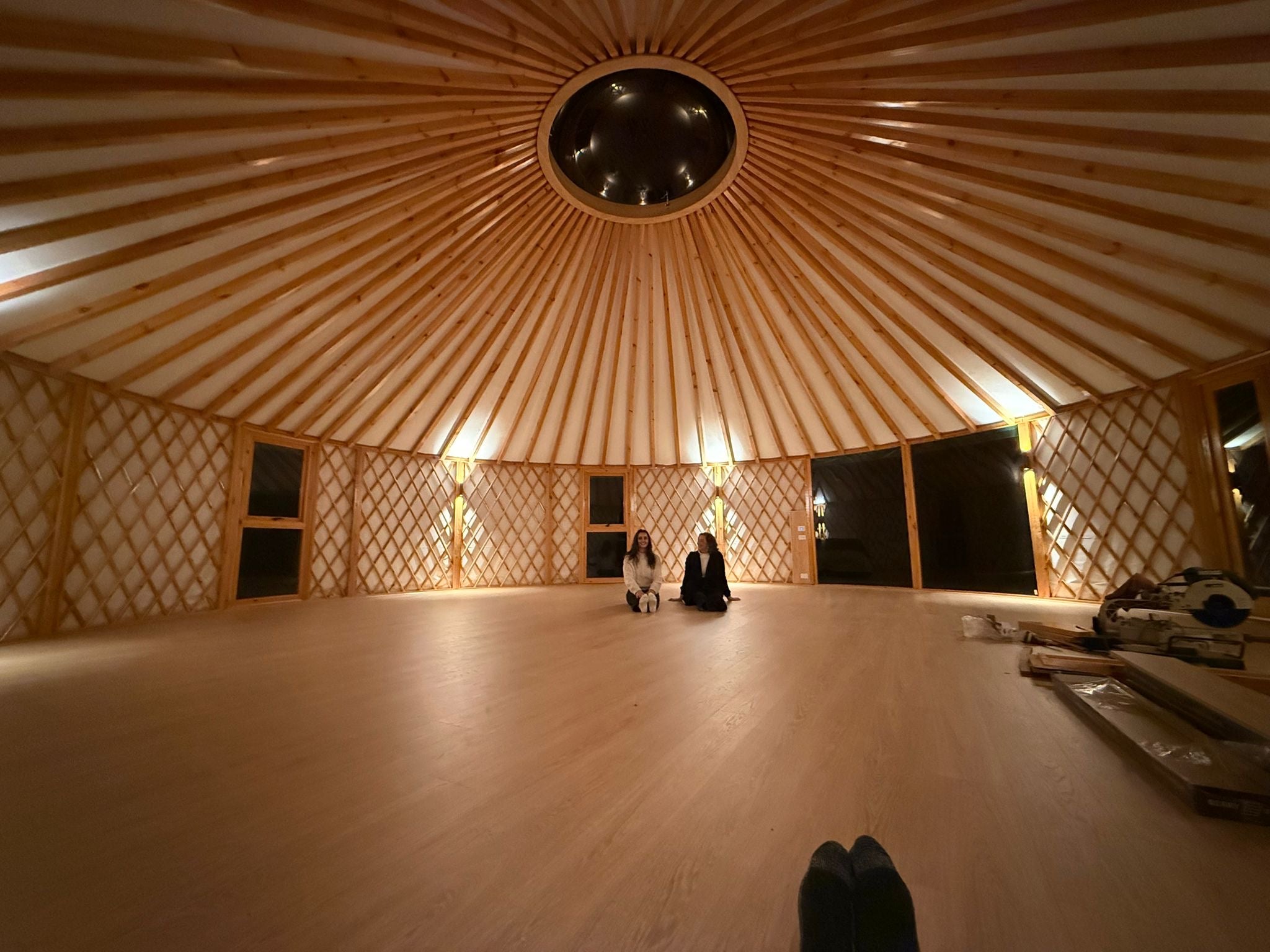 10m yurt interior with timber rafters, lattice walls and open floor space set up for a quiet retreat experience.