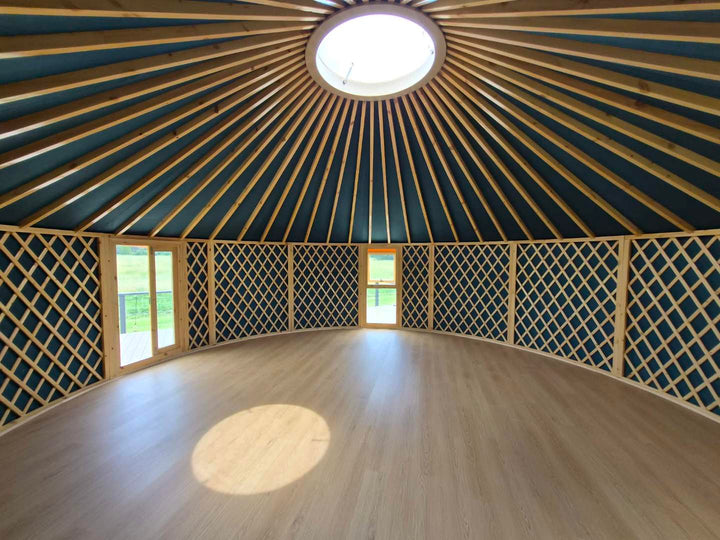 Interior of a yurt with wooden ceiling and lattice walls.