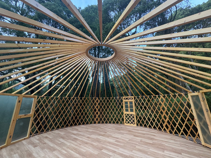 Wooden yurt structure with lattice walls and a clear sky