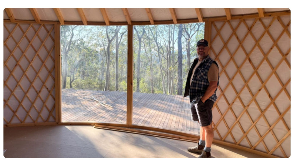 Interior of a yurt with two View Framer Windows framing bushland views from the circular space.