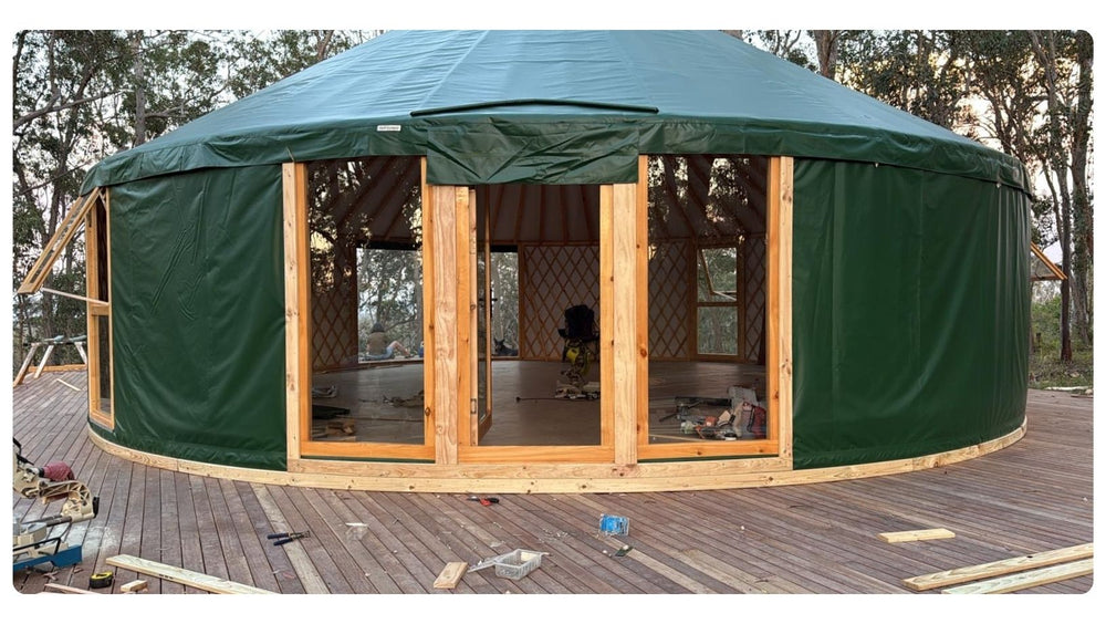Premium Combo Door on a green yurt, creating a wide entry point from the deck into the circular space.