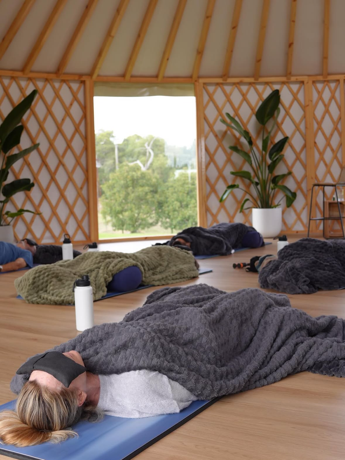 People lying on mats inside a yurt during a small group wellness session, demonstrating use for classes or retreats
