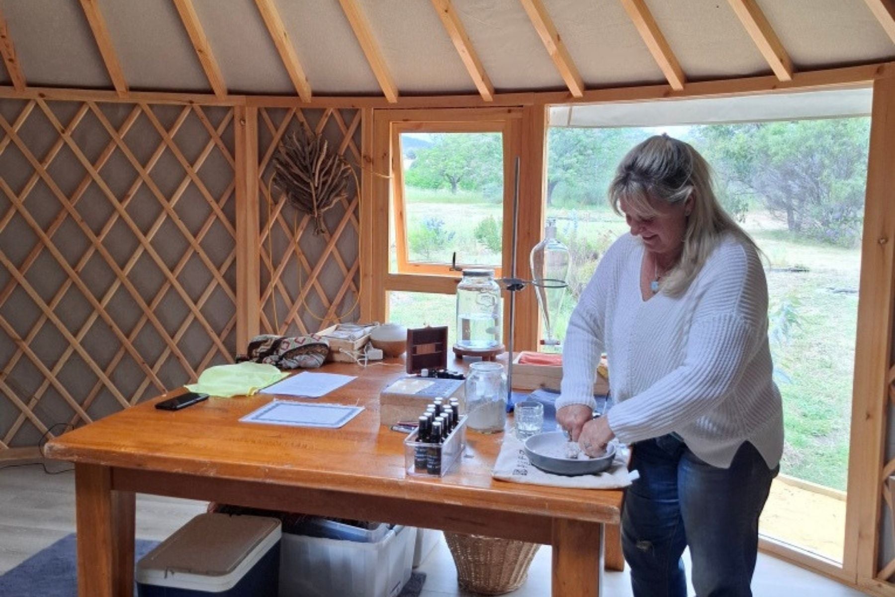 Woman working at a table inside a yurt with natural light and garden views through large windows