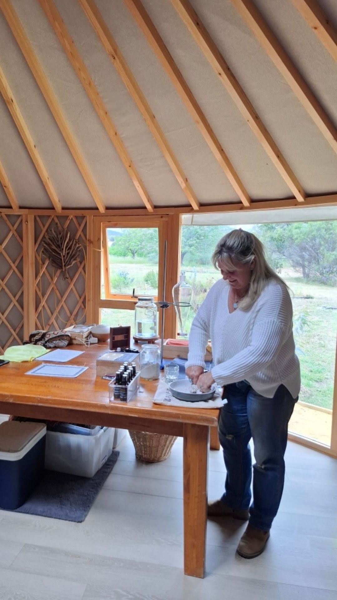 Woman working at a table inside a yurt with natural light and garden views through large windows