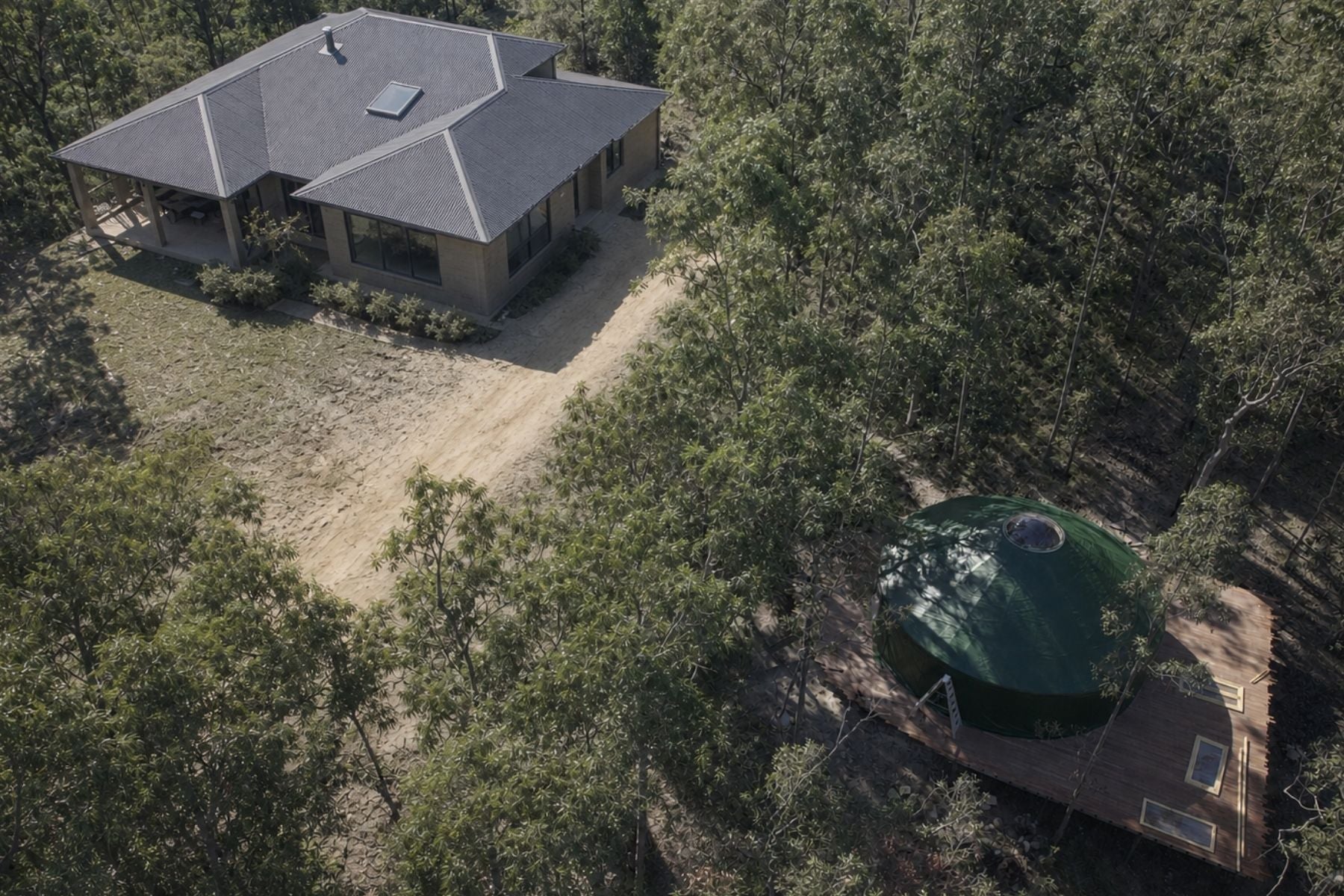 Aerial view of a rural property with a detached yurt positioned near the main house, showing how the structure integrates into existing land