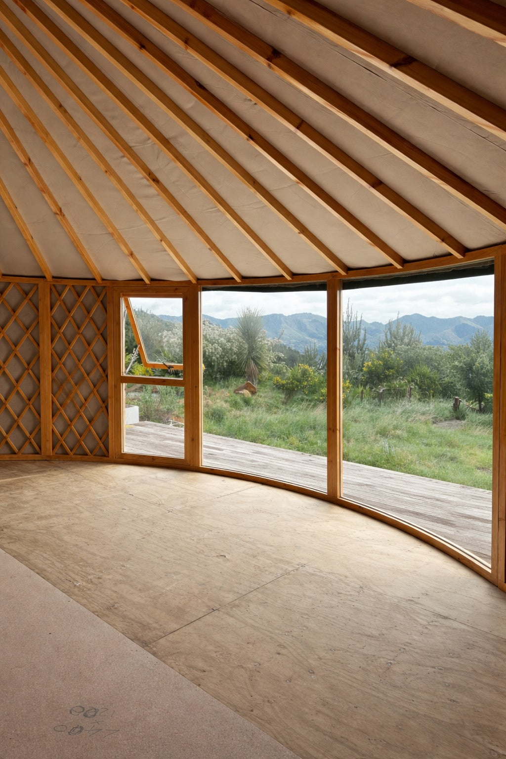Yurt interior with floor-to-ceiling windows and timber frame, positioned to capture natural views and maximise light and connection to the landscape